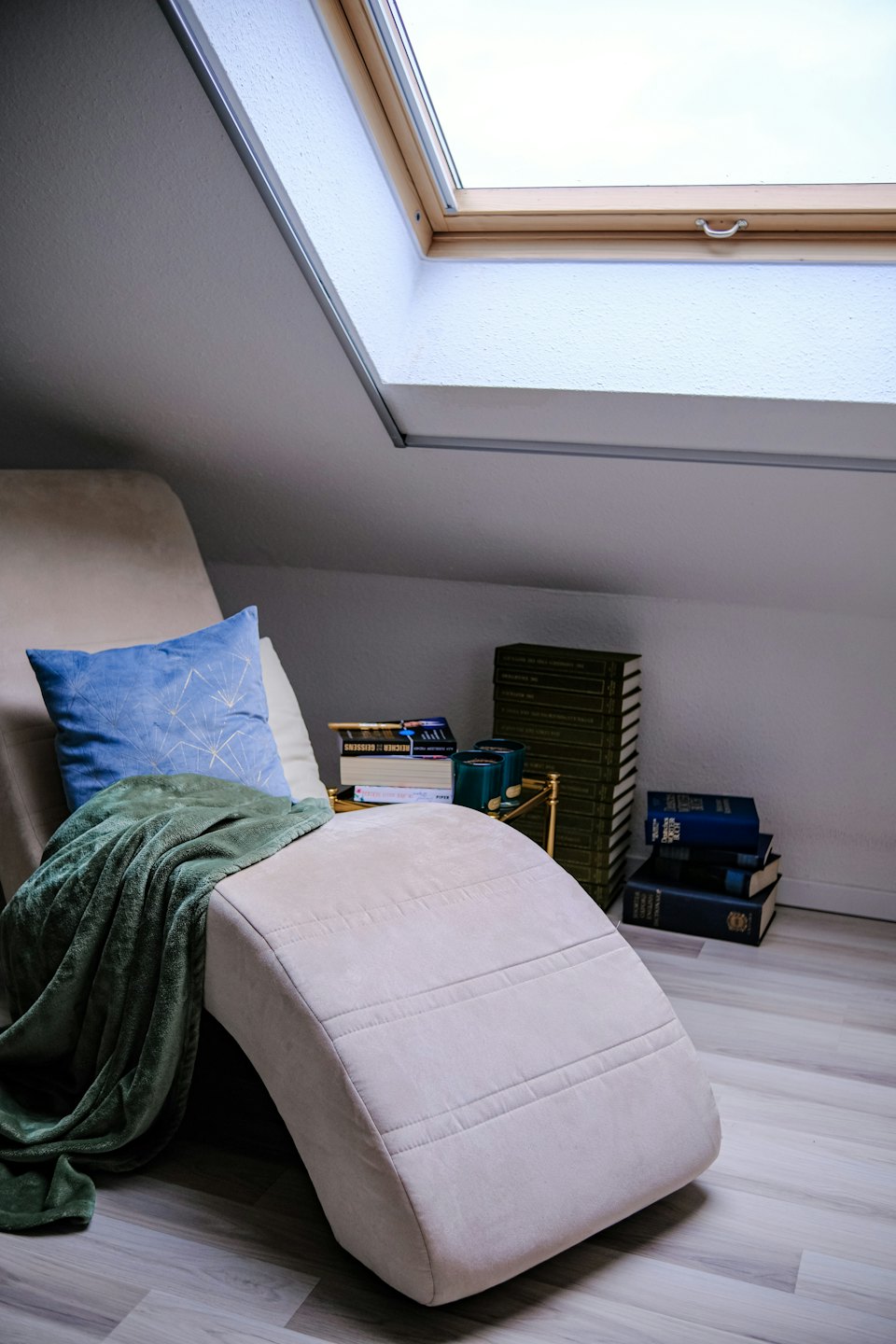 Beige Chaiselongue mit Büchern in einer sonnigen Ecke.